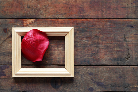 Romance concept. Red rose petal in picture frame on old wooden backgroundの写真素材