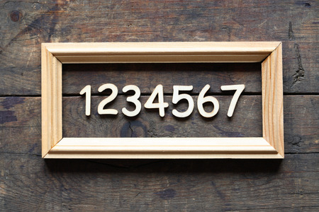 Set of wooden digits inside picture frame on wood backgroundの写真素材
