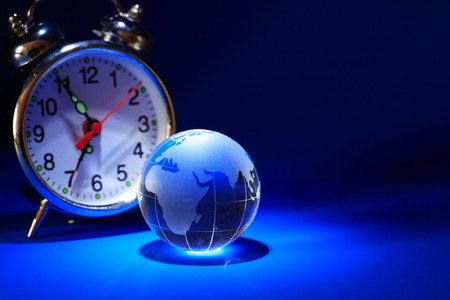 Glass globe near alarm clock on nice dark background