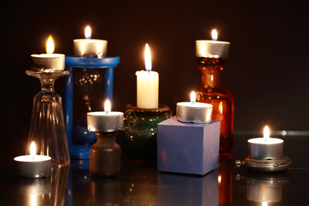 Set of lighting candles on various things against dark background
