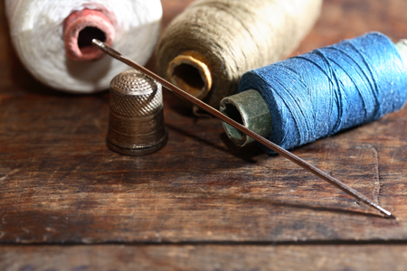 Thimble and needle near thread on old wooden backgroundの写真素材
