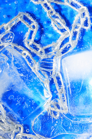 Metal chain under frozen water against blue backgroundの写真素材