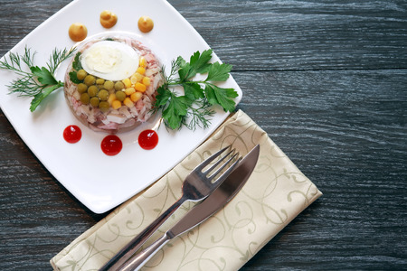 White plate with aspic near fork and knife on black tableの写真素材