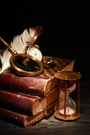 Vintage still life. Magnifying glass and pocket watch on old booksの写真素材