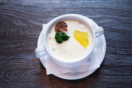 Bowl with mushroom soup in white bowl on dark wooden tableの写真素材