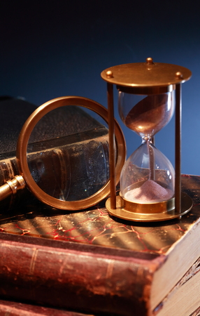 Vintage still life. Hourglass on old books against dark backgroundの写真素材
