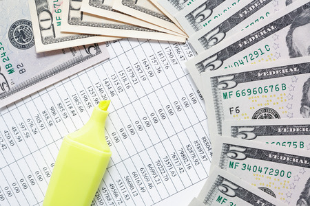 Yellow felt tip pen near money on paper background with digitsの写真素材