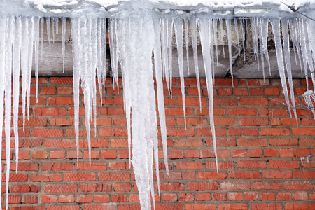 Icecles on background with red brick wallの写真素材