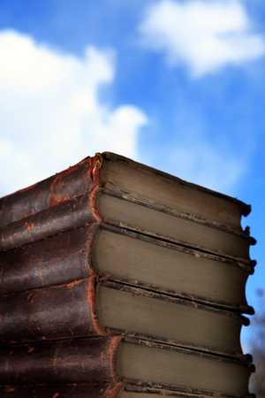 Stack of old books on blue sky background with free spaceの写真素材