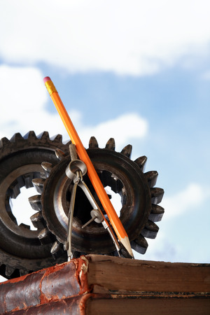 Divider near gears on stack of old books against blue sky backgroundの写真素材