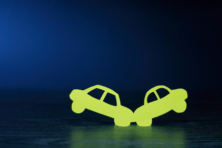 Crush of two cars made from yellow paper on dark backgroundの写真素材