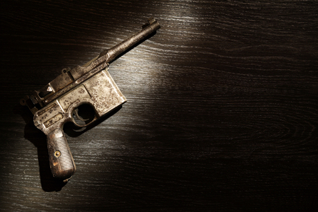Old military pistol on dark background under beam of lightの写真素材