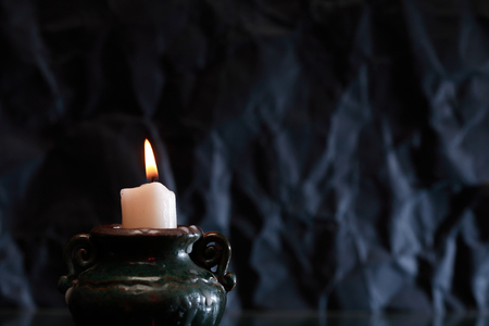 One lighting candle with reflection against dark backgroundの写真素材