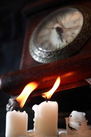 Vintage still life concept photo with lighting candles near old clockの写真素材