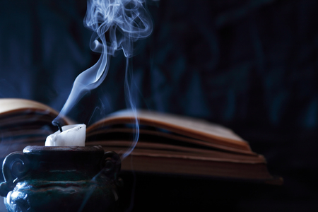 Extinguished candle and blue smoke near old bookの写真素材