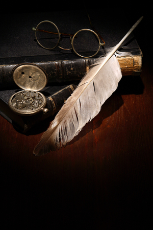 Quill pen and spectacles on old booksの写真素材