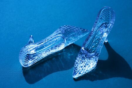 Pair of nice glass slippers on blue background with shadowの写真素材