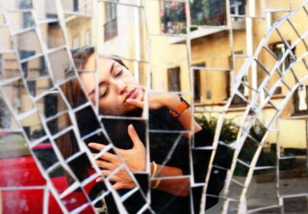 The beauty girl's reflection in the mirror on building wallの写真素材
