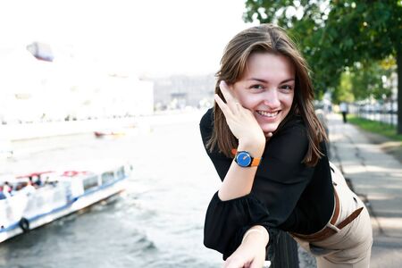 Beautiful young woman on embankment near river in cityの写真素材