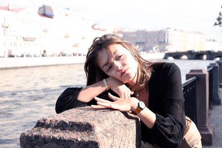 Beautiful young woman on embankment near river in cityの写真素材