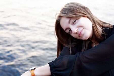Beautiful young woman portrait against water backgroundの写真素材