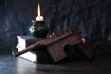 Still life with old military handgun near ancient books and candleの写真素材