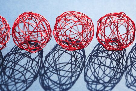 Set of red balls made from wire in a row against sun lightの写真素材