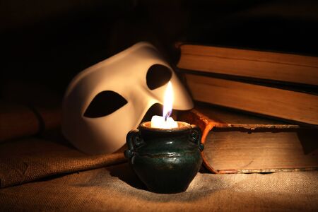 Vintage still life with candle near mask and booksの写真素材