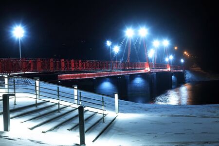 Night landscape with nice red bridge across river in winter at nightの写真素材
