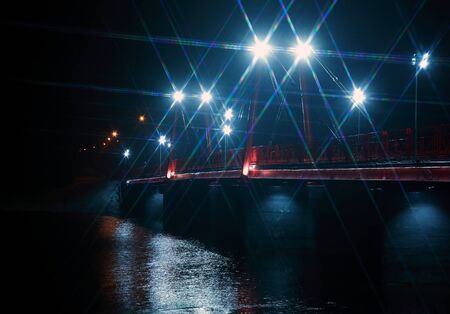 Night landscape with nice red bridge across river in winter at nightの写真素材