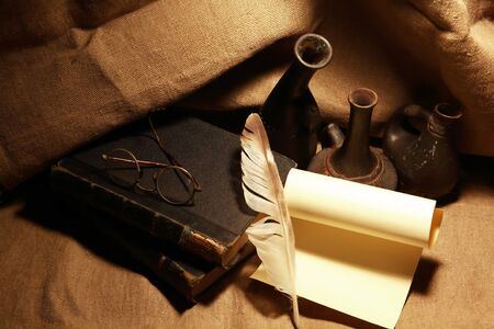 Vintage still life with old books and quill pen on canvas backgroundの写真素材