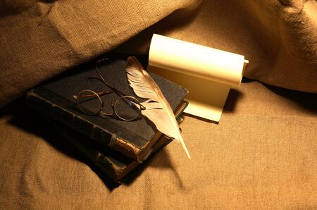 Vintage still life with old books and quill pen on canvas backgroundの写真素材