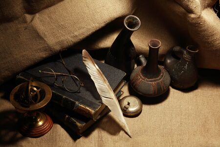 Vintage still life with old books and quill pen on canvas backgroundの写真素材