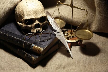 Old books and quill pen near human skull on canvas backgroundの写真素材