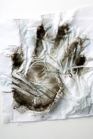 Black dirty handprint on white paper napkinの写真素材