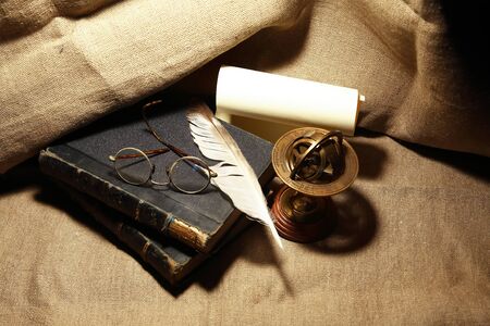 Vintage still life with old books and quill pen on canvas backgroundの写真素材