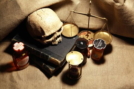 Old books and quill pen near human skull on canvas backgroundの写真素材
