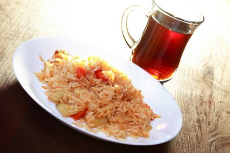 White plate with pilaf near cup of tea on wooden tableの写真素材
