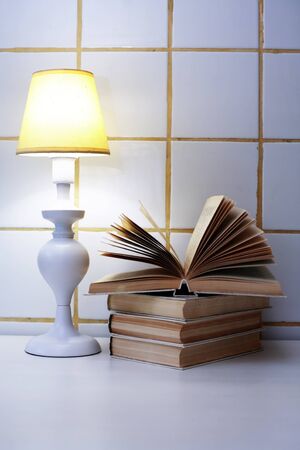 Elegance white desk lamp with yellow lampshade near open bookの写真素材