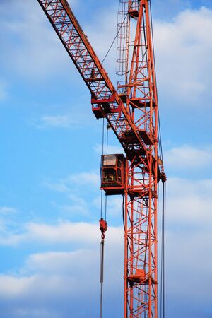 Industrial theme. Red construction crane against blue skyの写真素材