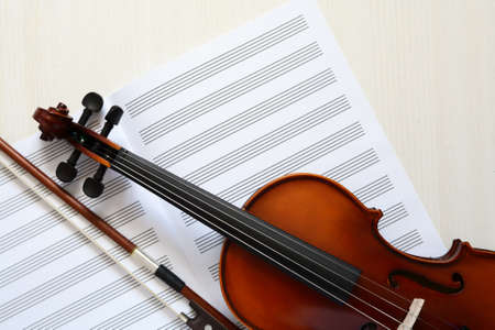 Nice violin and open blank music book on white wooden backgroundの写真素材