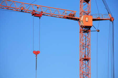 Industrial theme. Red construction crane against blue skyの写真素材