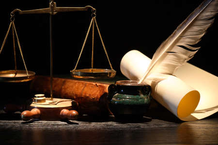 Justice or science concept. Weight scale near old book and quill pen on dark backgroundの写真素材