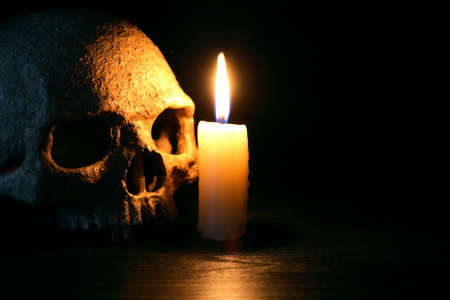 Vintage still life with lighting candle near human skullの写真素材
