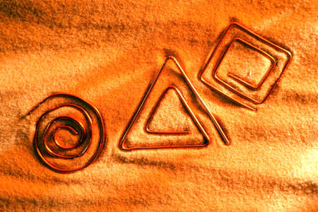 Abstract symbols made from copper wire on sand surfaceの写真素材