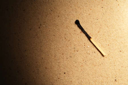 One burnt match on sand background with beam of lightの写真素材