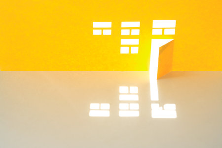 House made from yellow paper with few windows and open doorの写真素材