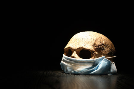 Covid concept. Blue Medical Disposable Face Mask On Human Skullの写真素材