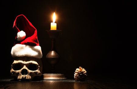 The death of Santa Claus. Human skull with Christmas hat near lighting candleの写真素材