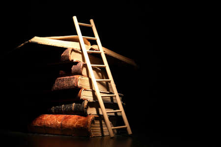 Education concept. Stack of old books and ladder on dark backgroundの写真素材